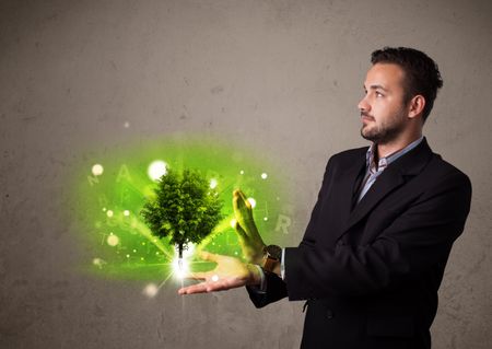 Young businessman holding a glowing tree in his hand