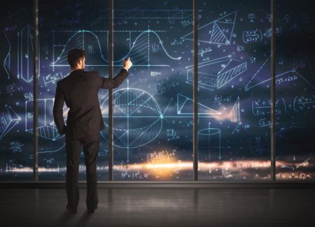 Businessman drawing business graphs on glass wall 