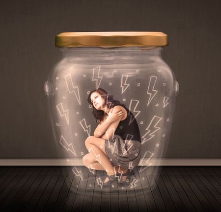 Businesswoman inside a glass jar with lightning drawings concept on background