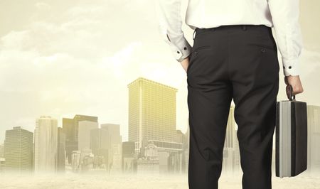 Businessman from the back in front of a city view with sunshine