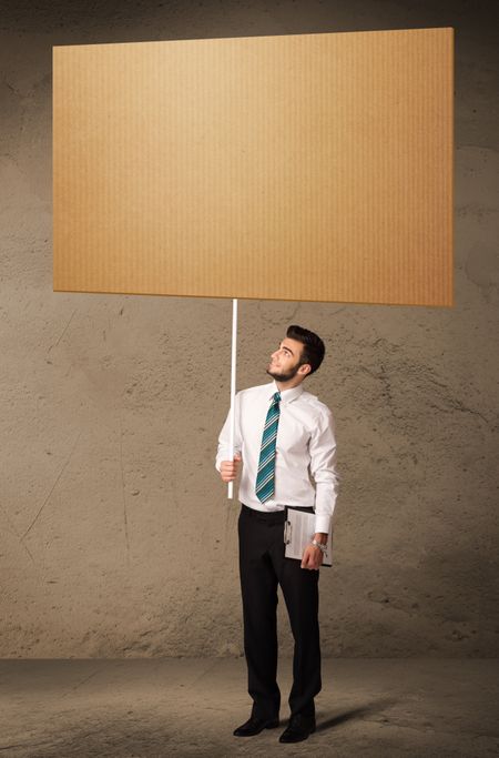 Young businessman holding a blank brown cardboard 