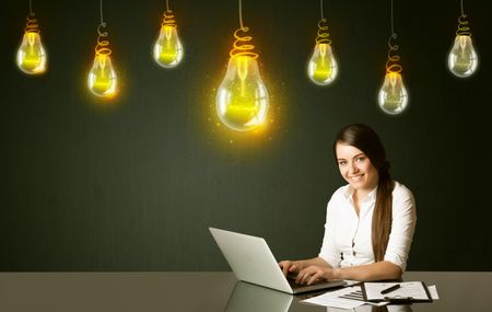 Businesswoman sitting at the black table with idea bulbs on the background 