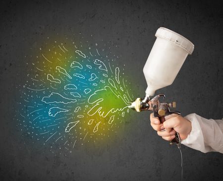 Worker with airbrush gun paints colorful lines and splashes concept