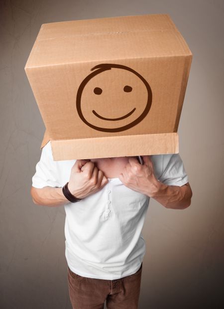 Young man standing and gesturing with a cardboard box on his head with smiley face