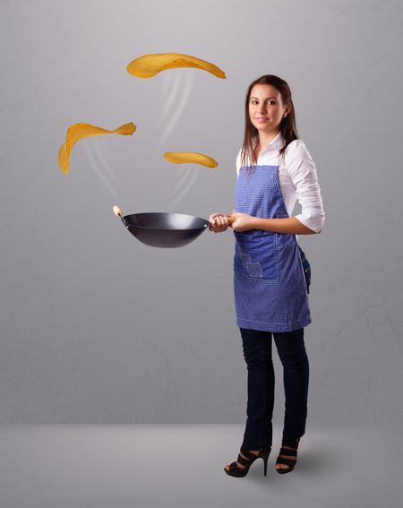 Beautiful young woman making pancakes