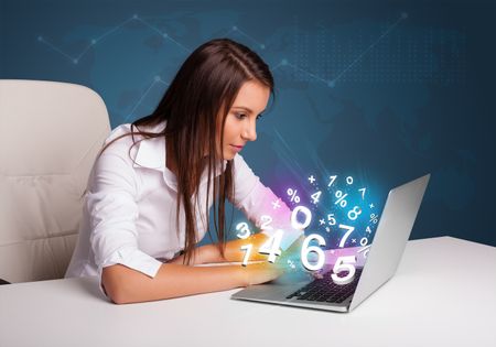 Beautiful young woman sitting at desk and typing on laptop with 3d numbers comming out