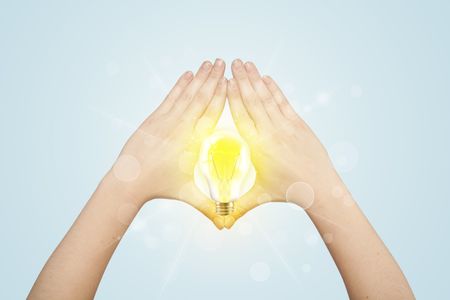 Hands creating a form with yellow light bulb in the center