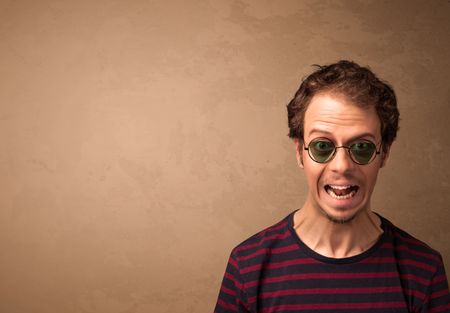 Portrait of a young pretty man with sunglasses and copyspace on brown background