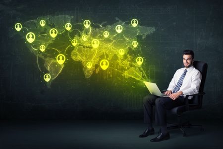 Businessman in office with laptop and social network world map concept on background