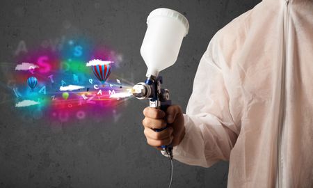 Worker with airbrush and colorful abstract clouds and balloons concept