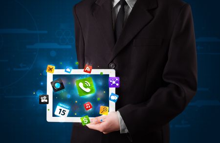 Young businessman holding a tablet with modern colorful apps and icons