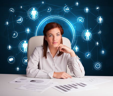 Young businesswoman sitting at desk with social network icons