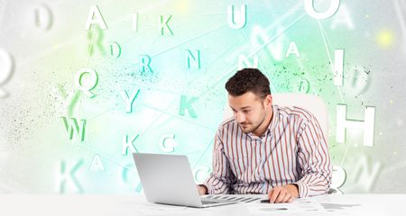 Business man at white desk with green word cloud