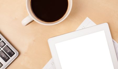 Tablet pc with copy space and a cup of coffee on a wooden work table close-up