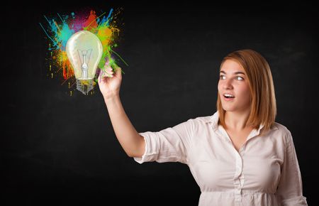 Young lady drawing a colorful light bulb with colorful splashes on white background