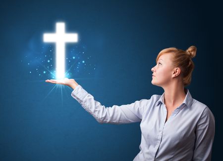 Young businesswoman holding a glowing cross in her hand
