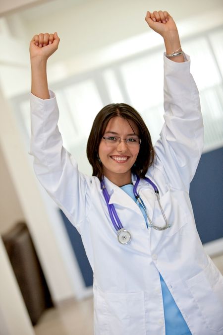 happy succesful female doctor at a hospital smiling with her arms up
