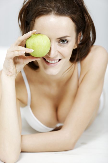 Attractive young woman in white underwear with a fresh apple