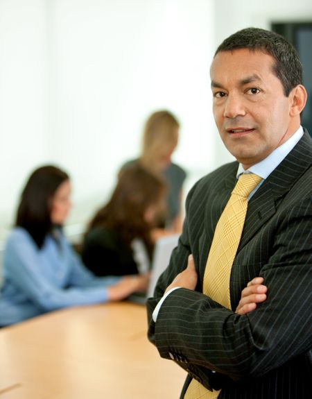 business man portrait in an office with his team behind him