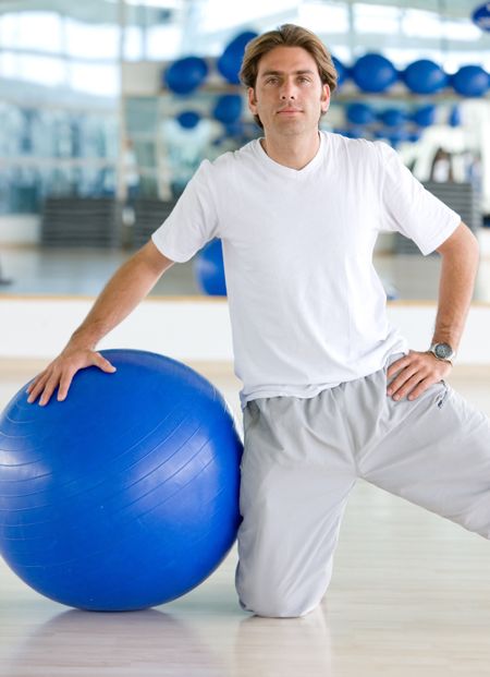 gym man doing pilates exercises on a blue ball