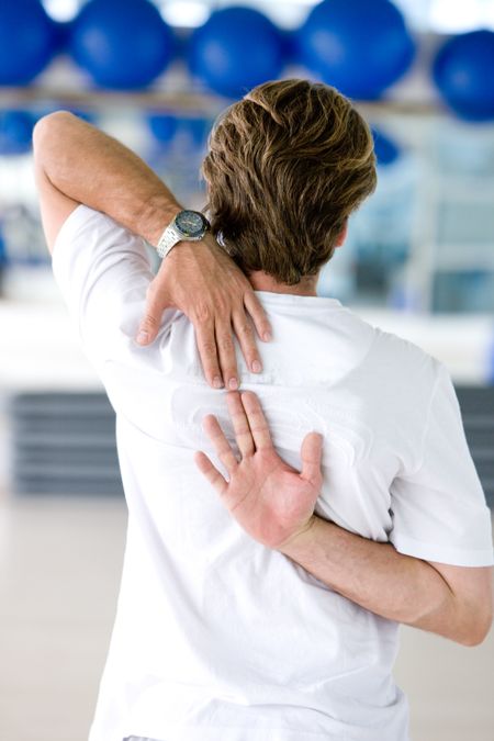 rear view of a gym man stretching arms and back at the gym