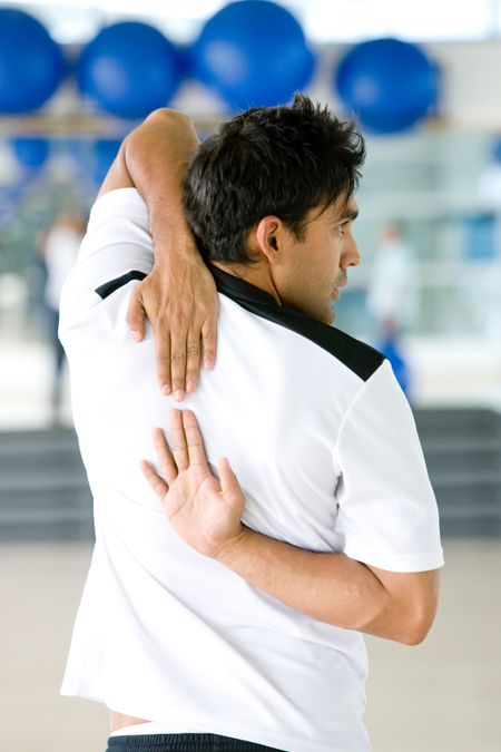 rear view of a gym man stretching arms and back at the gym