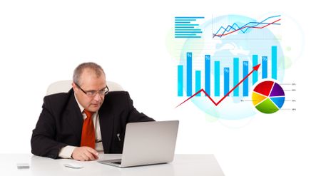 Businessman sitting at desk with laptop and statistics, isolated on white