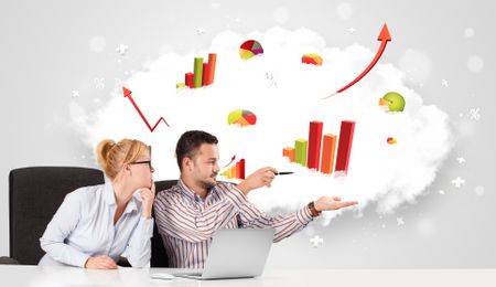 Young businessman and businesswoman with cloud in the background containing colorful graphs and diagrams