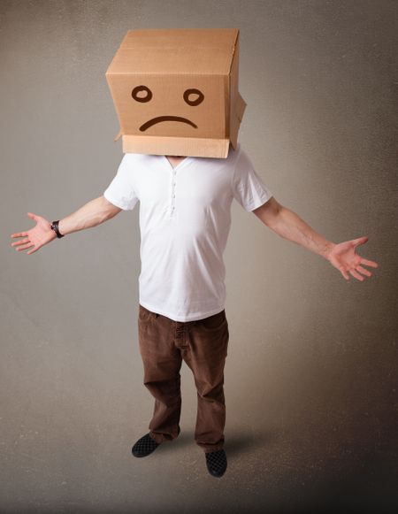 Young man standing with a brown cardboard box on his head with sad face