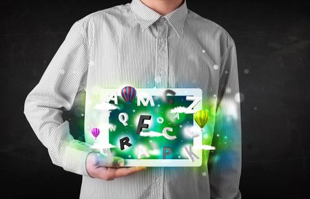 Young person showing white tablet with abstract letters and sky