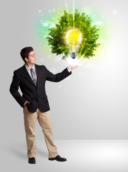 Young man presenting idea light bulb with green tree concept