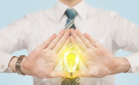 Hands creating a form with yellow light bulb in the center