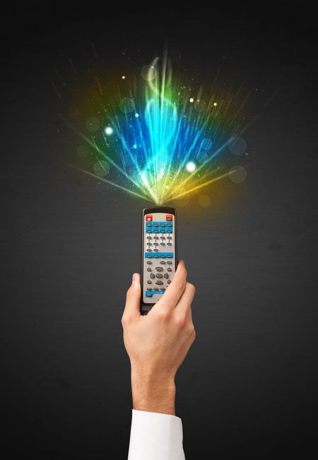 Hand holding a remote control, shining and explosive signal coming out of it
