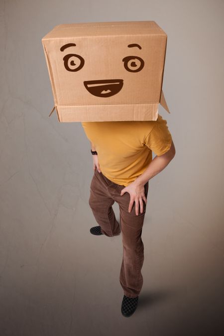 Young man standing and gesturing with a cardboard box on his head with smiley face