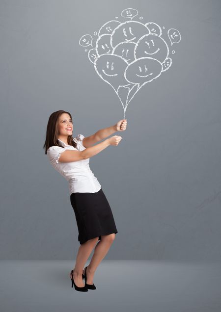 Happy young woman holding smiling balloons drawing