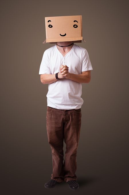 Young man standing and gesturing with a cardboard box on his head with smiley face