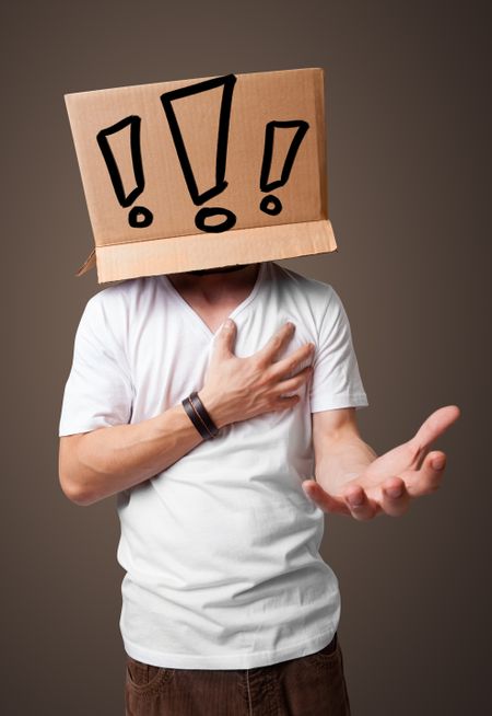 Young man standing and gesturing with a cardboard box on his head with exclamation point