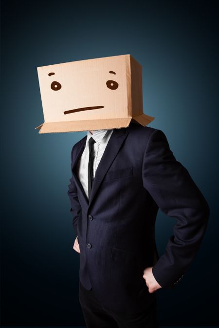 Businessman standing and gesturing with a cardboard box on his head with straight face