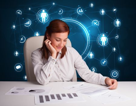 Young businesswoman sitting at desk with social network icons
