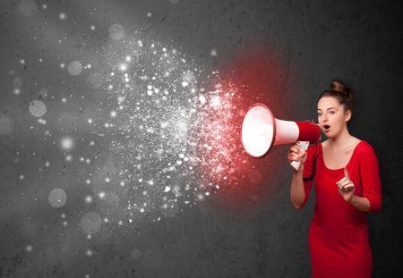 Woman shouting into megaphone and glowing energy particles explode concept