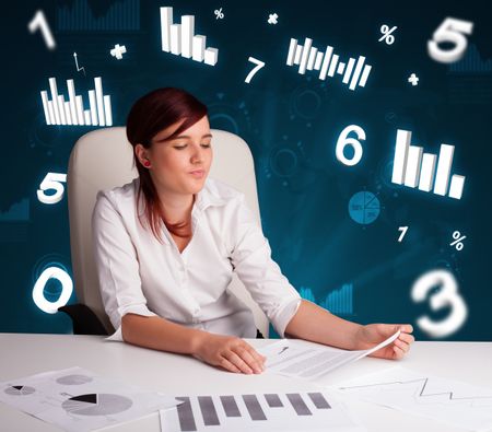 Pretty young businesswoman sitting at desk with diagrams and statistics