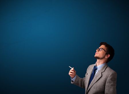 Handsome young man smoking cigarette with copy space