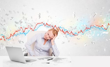 Business woman sitting at table with stock market graph 3d letters