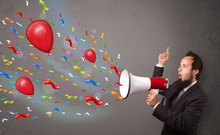 Young guy having fun, shouting into megaphone with balloons and confetti