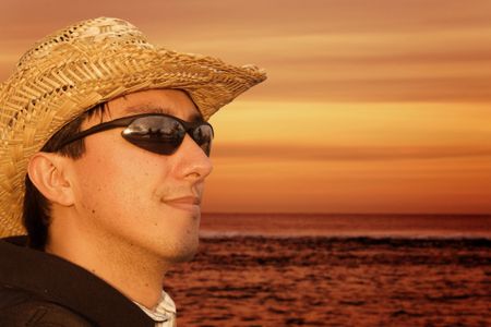 man wearing a hat and sunglasses by the beach