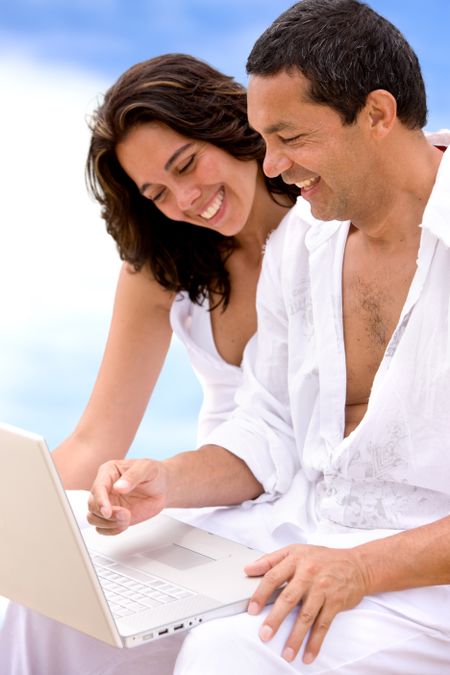 Beach couple on a computer smiling