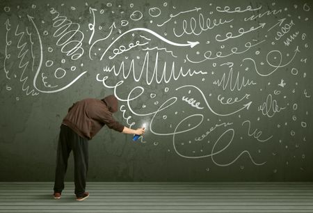 Young urban painter drawing curly lines and arrows on the wall