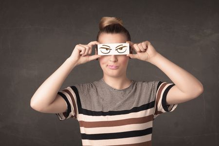 Young person holding paper with angry eye drawing concept