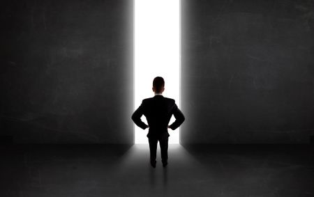 Business person looking at wall with light tunnel opening concept
