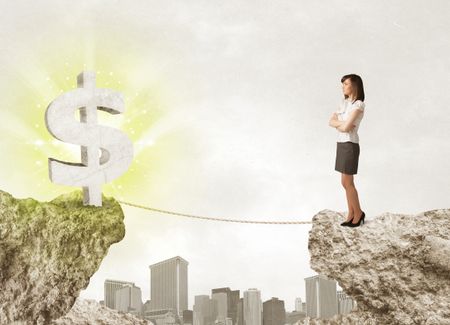 Businesswoman standing on the edge of mountain with a shining dollar mark on the other side 